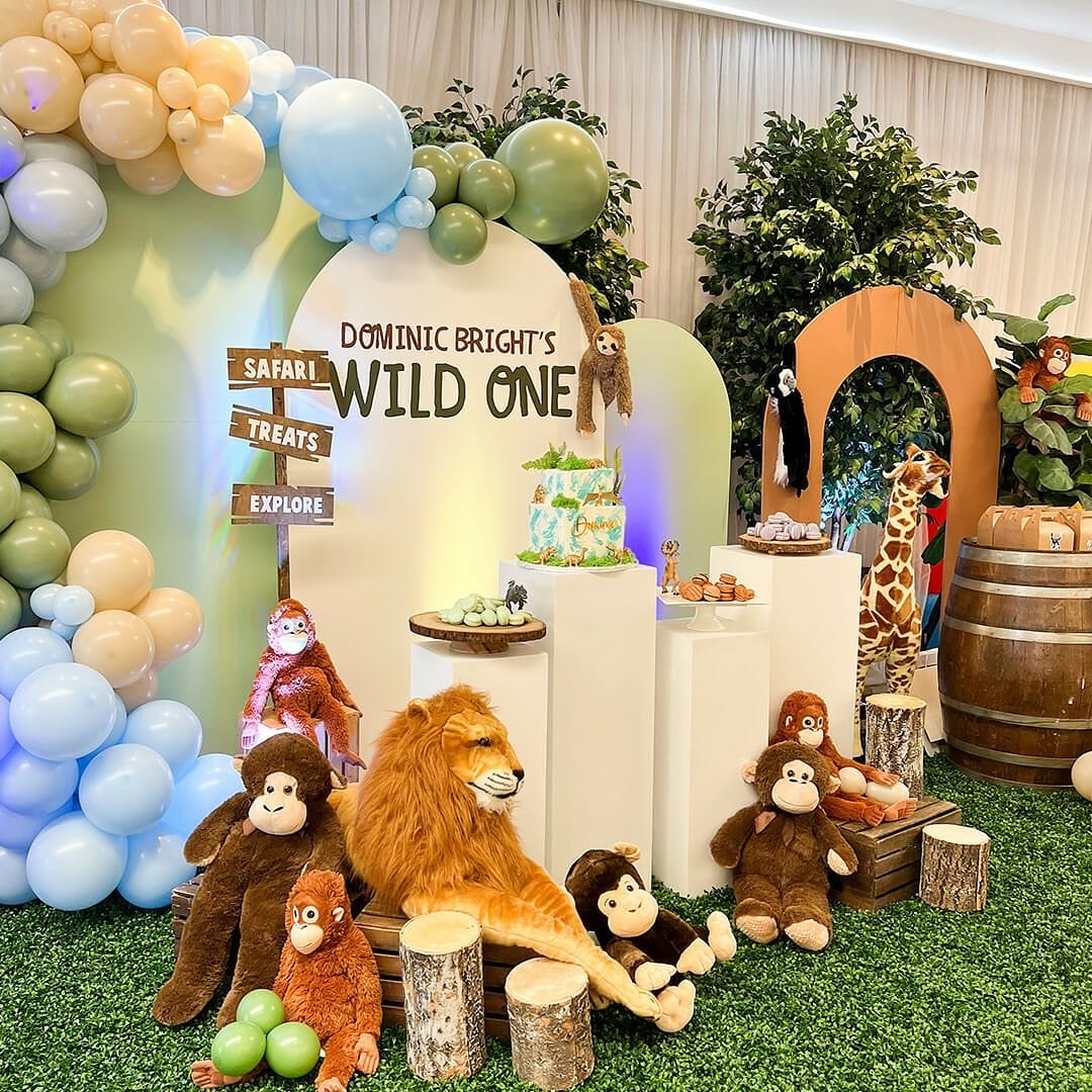 Safari-themed birthday party setup with stuffed animal decorations, colorful balloons, greenery, and dessert displays, ideal inspiration captured by By Kyla Studio. This image is part of the blog post "10+ Kids Birthday Photographers in New York City."